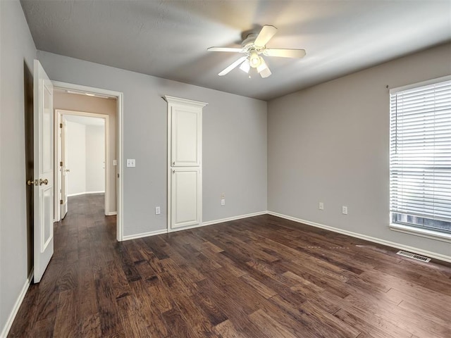 interior space with visible vents, multiple windows, baseboards, and dark wood-style flooring