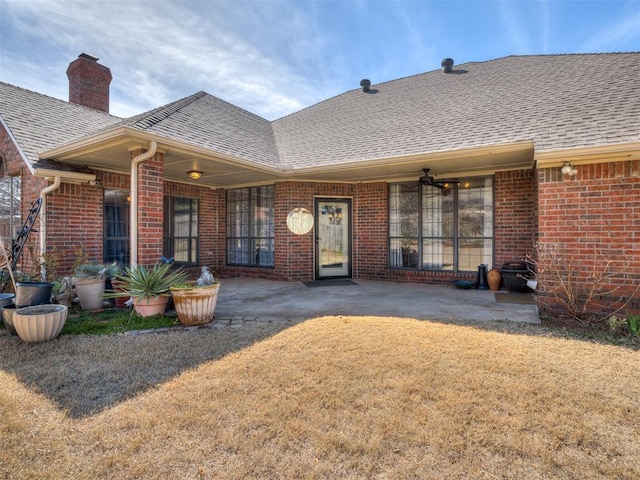 rear view of house featuring a yard, brick siding, and a shingled roof