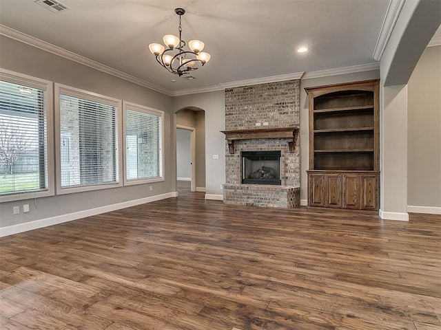 unfurnished living room with an inviting chandelier, crown molding, arched walkways, and a healthy amount of sunlight