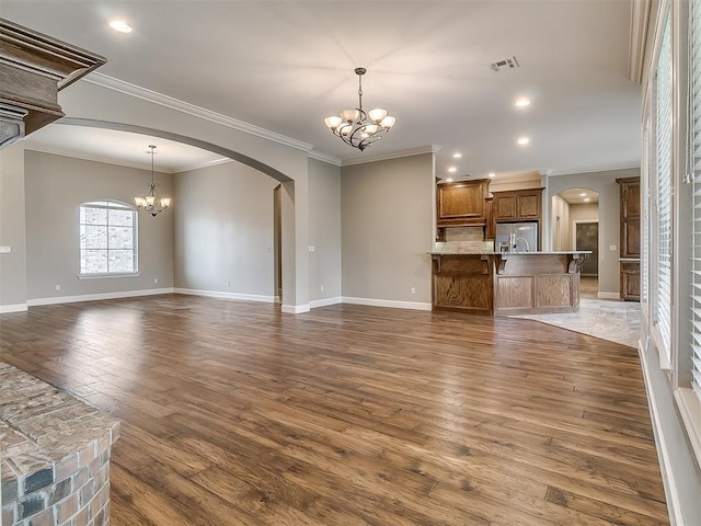 unfurnished living room with visible vents, arched walkways, and a chandelier