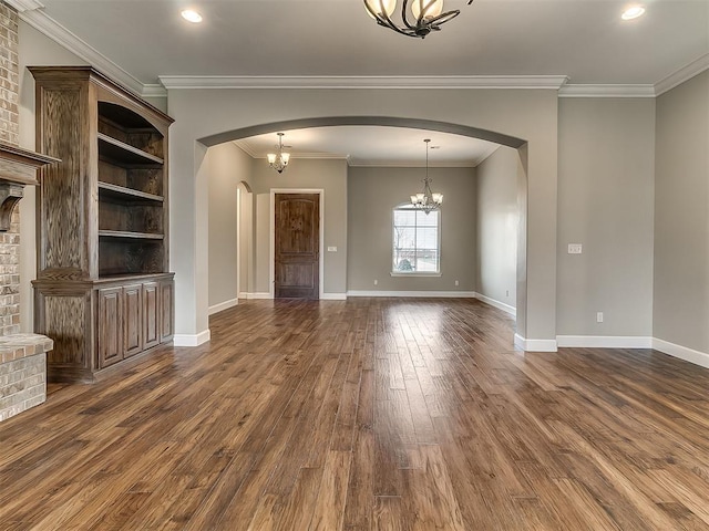 unfurnished living room featuring baseboards, dark wood finished floors, arched walkways, crown molding, and a notable chandelier