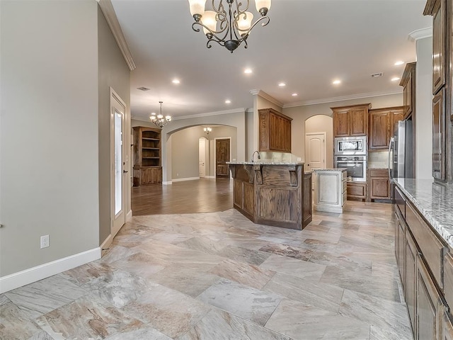 kitchen featuring a breakfast bar, arched walkways, ornamental molding, appliances with stainless steel finishes, and a chandelier