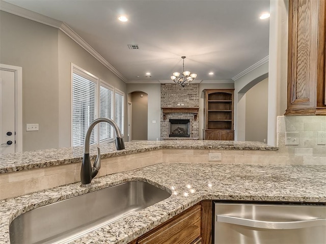 kitchen featuring tasteful backsplash, visible vents, dishwasher, arched walkways, and a sink