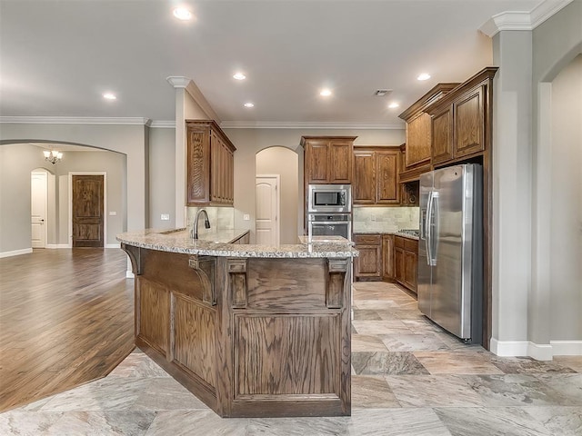 kitchen featuring a peninsula, light stone countertops, arched walkways, and appliances with stainless steel finishes