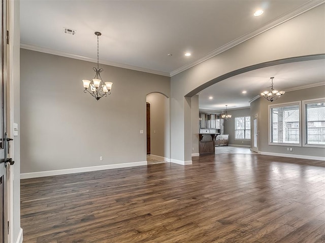 unfurnished living room with arched walkways, an inviting chandelier, dark wood finished floors, and ornamental molding