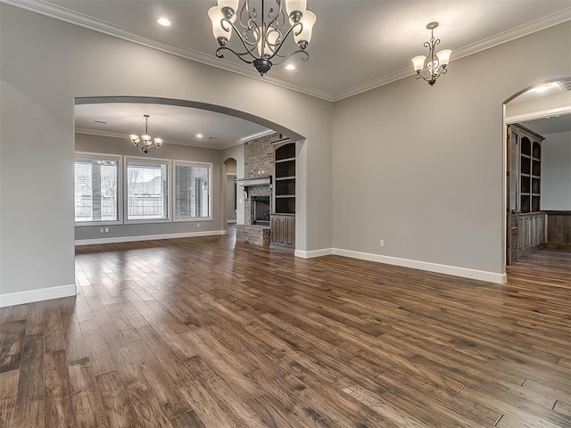 unfurnished living room with dark wood-style floors, arched walkways, baseboards, and a chandelier