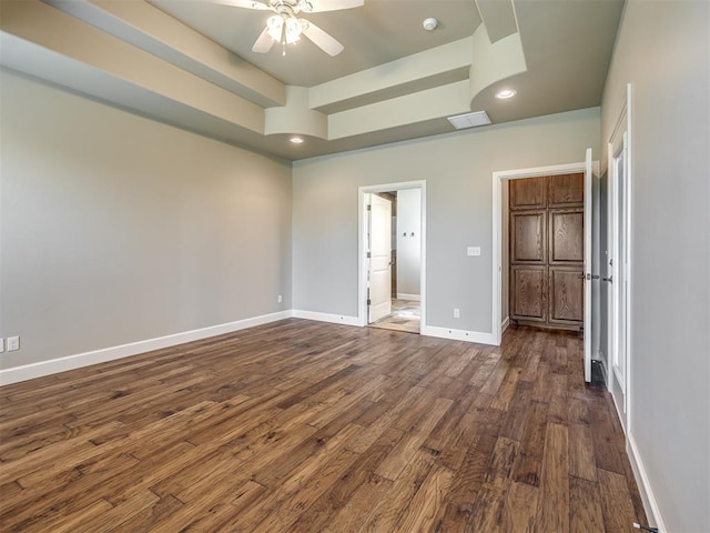 unfurnished bedroom with visible vents, baseboards, dark wood finished floors, a tray ceiling, and recessed lighting