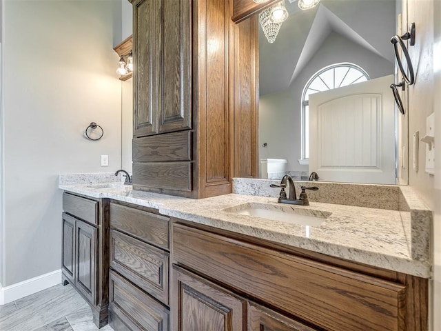 full bath with a sink, baseboards, double vanity, and vaulted ceiling