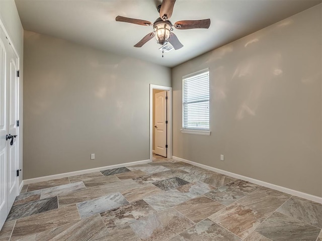 spare room with stone finish floor, baseboards, and ceiling fan