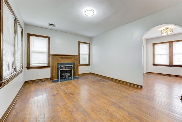 unfurnished living room featuring visible vents, baseboards, hardwood / wood-style floors, and a tile fireplace