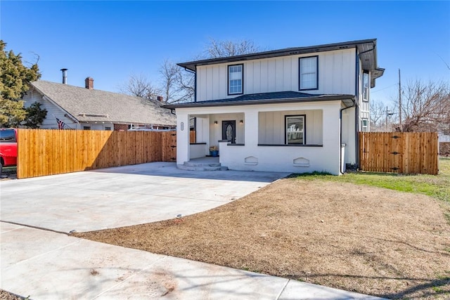 view of front of property with brick siding, covered porch, board and batten siding, and fence