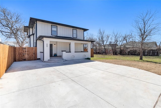 view of front of home featuring a porch, fence, board and batten siding, and a front lawn