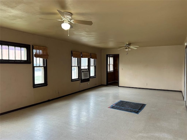 empty room featuring cooling unit, ceiling fan, light floors, and baseboards