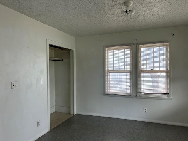 unfurnished bedroom with a textured ceiling and baseboards