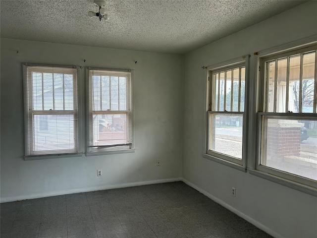 unfurnished room featuring tile patterned floors, baseboards, and a textured ceiling