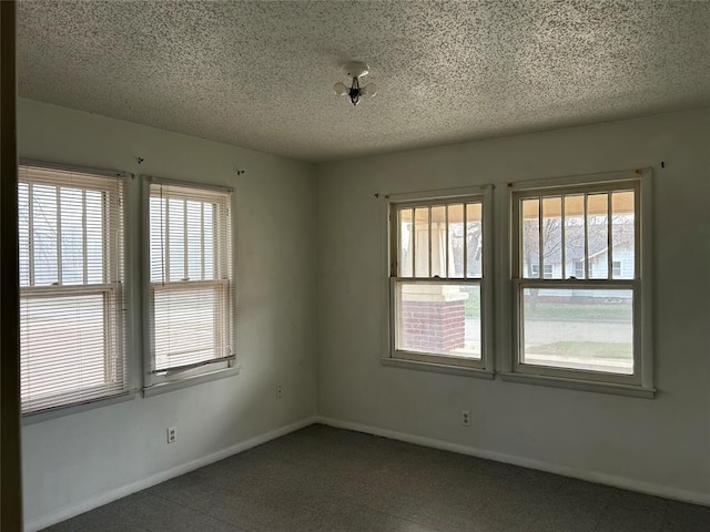 empty room with a textured ceiling and baseboards