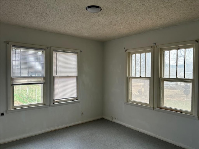 spare room featuring plenty of natural light, baseboards, and a textured ceiling