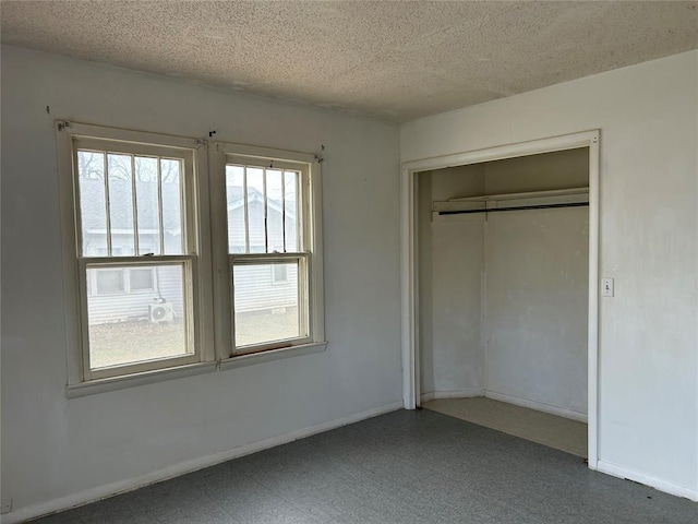 unfurnished bedroom with tile patterned floors, a closet, baseboards, and a textured ceiling