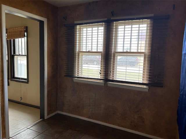 spare room with tile patterned flooring and baseboards