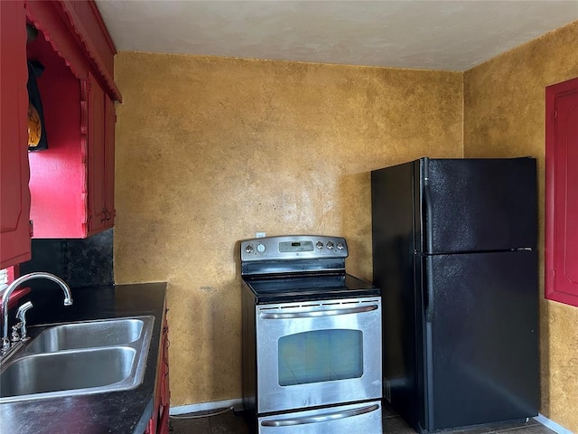 kitchen with electric range, freestanding refrigerator, and a sink