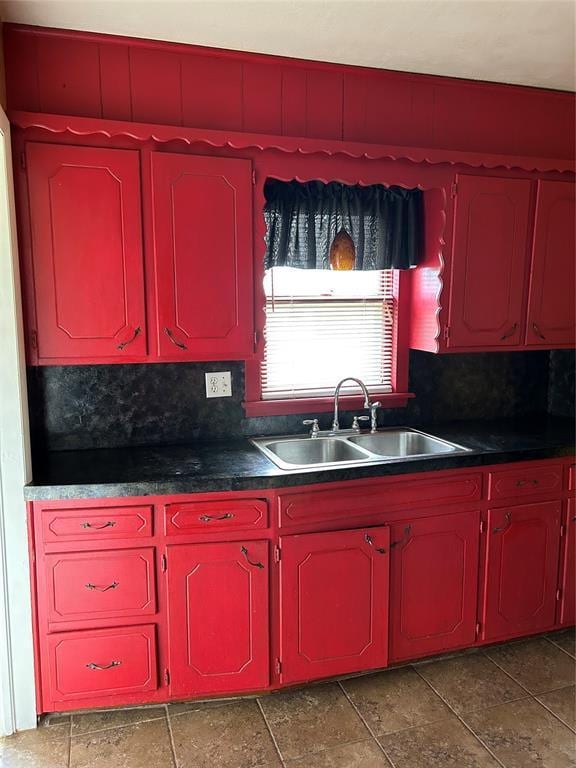 kitchen with dark countertops, tasteful backsplash, and a sink