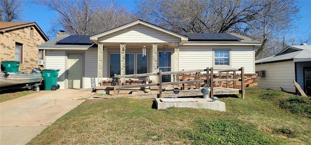 rear view of house featuring solar panels, a porch, and a yard