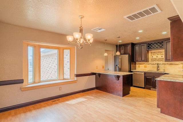 kitchen with a peninsula, visible vents, appliances with stainless steel finishes, and a sink