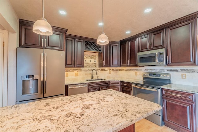 kitchen with dark brown cabinets, light stone countertops, stainless steel appliances, and a sink