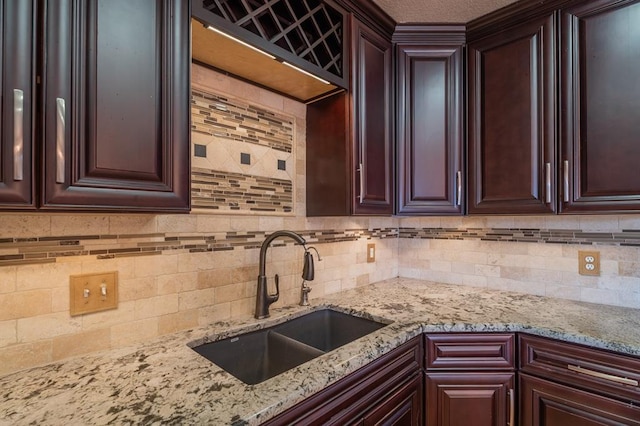 kitchen featuring light stone countertops, tasteful backsplash, and a sink