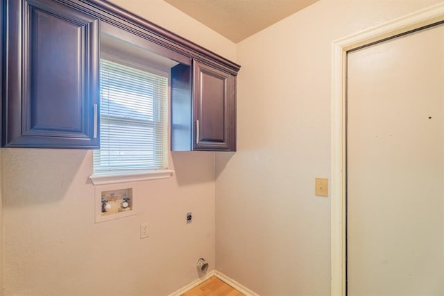 laundry room featuring electric dryer hookup, washer hookup, light wood-style flooring, cabinet space, and baseboards