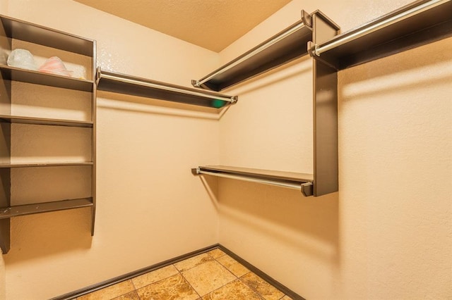 walk in closet featuring stone finish flooring