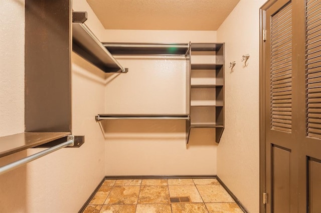 walk in closet featuring visible vents and stone finish floor