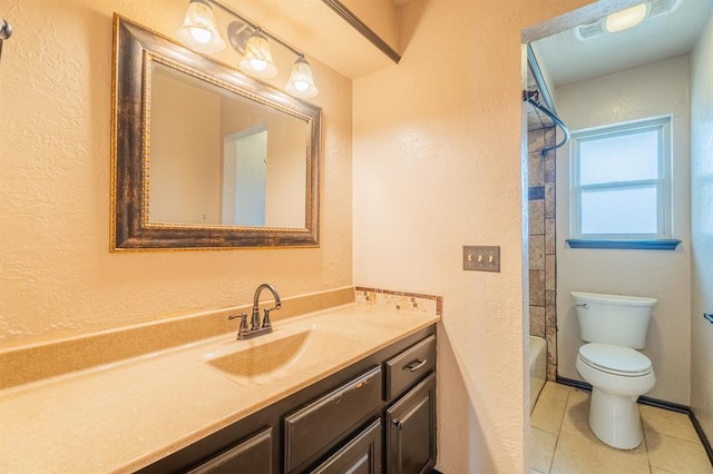 bathroom featuring tile patterned floors, toilet, vanity, and a textured wall