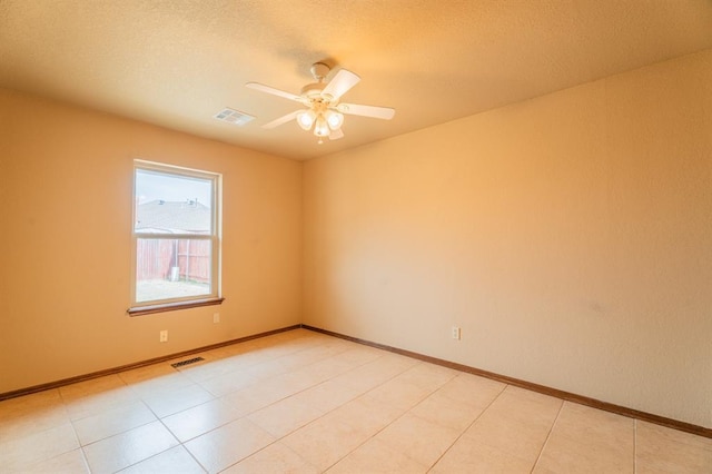 empty room featuring a textured ceiling, baseboards, visible vents, and ceiling fan