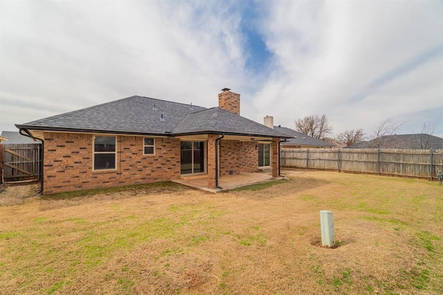 back of property featuring a yard, a patio, a fenced backyard, and a chimney