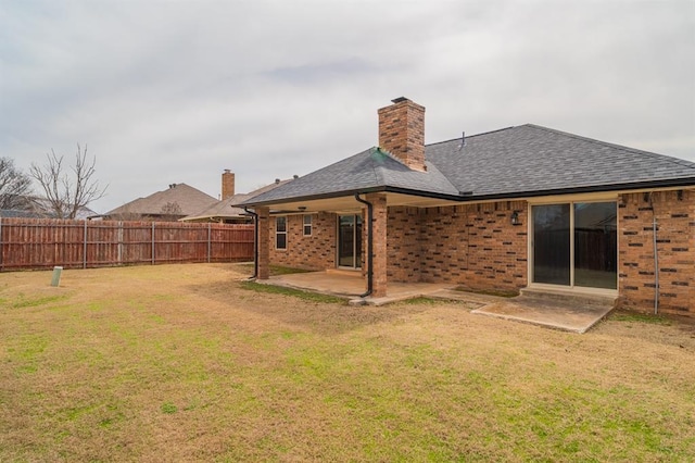 rear view of property with fence, a shingled roof, a lawn, a patio area, and brick siding