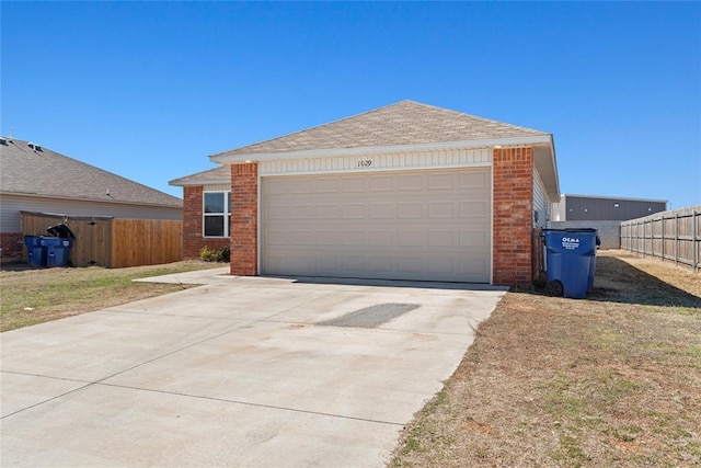 garage featuring driveway and fence