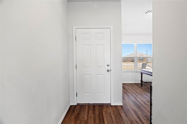 corridor with visible vents, baseboards, and dark wood-type flooring