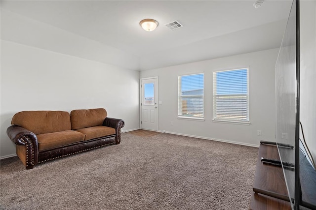 carpeted living area featuring a wealth of natural light, visible vents, and baseboards