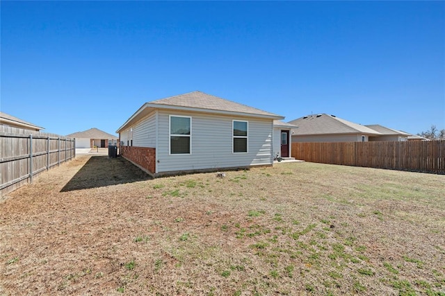 rear view of property with a fenced backyard and a lawn