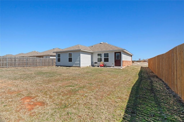 back of property featuring a fenced backyard and a lawn