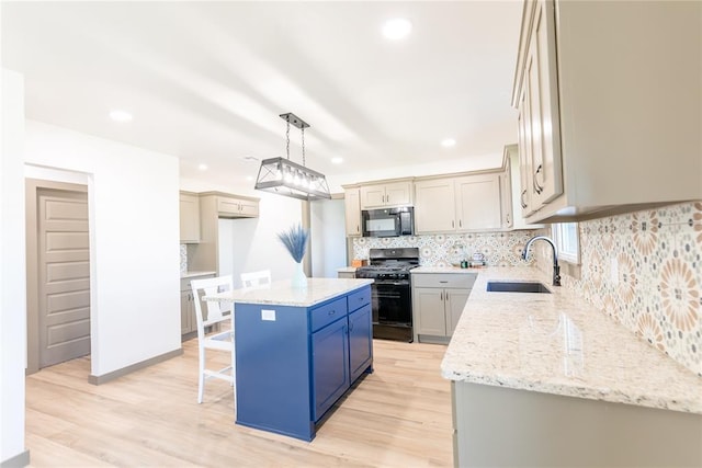 kitchen with tasteful backsplash, a center island, a kitchen breakfast bar, black appliances, and a sink