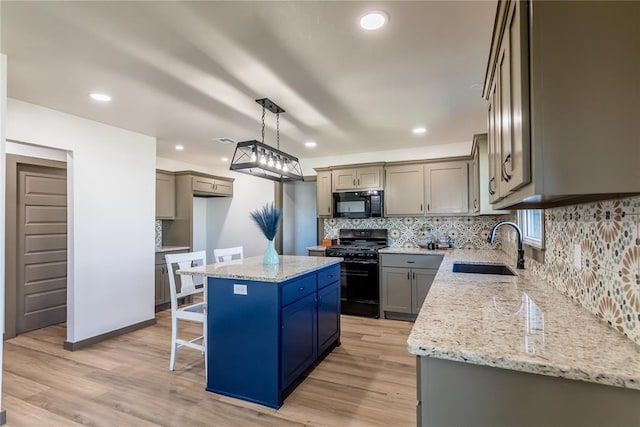 kitchen with light wood-style flooring, a sink, black appliances, tasteful backsplash, and a center island