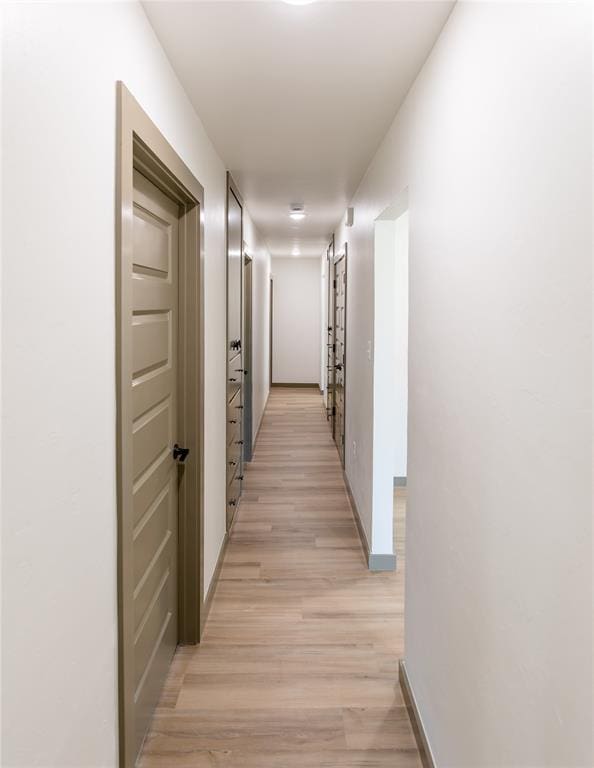 corridor with baseboards and light wood-style flooring