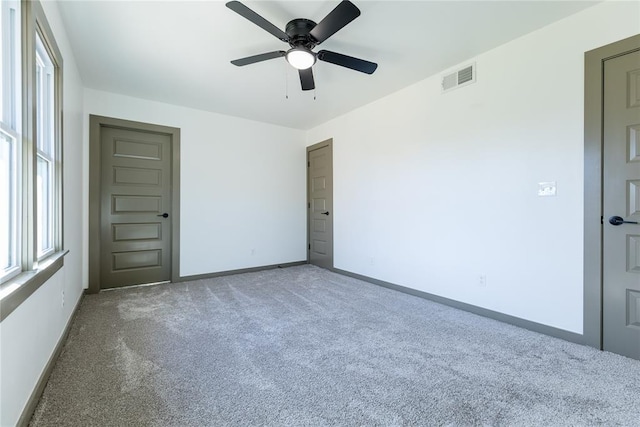 carpeted spare room with a ceiling fan, baseboards, and visible vents