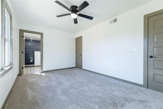 spare room with visible vents, light carpet, baseboards, and a ceiling fan