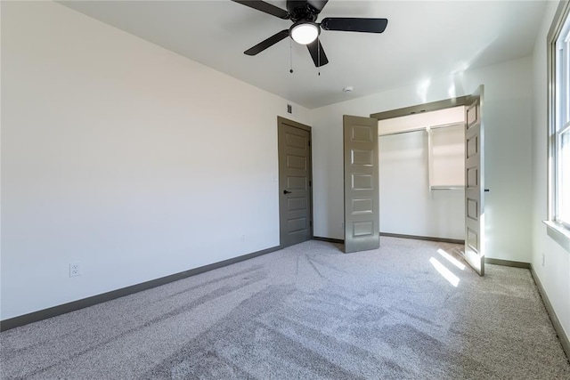 unfurnished bedroom featuring light carpet, a closet, baseboards, and a ceiling fan