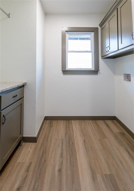 clothes washing area with light wood-type flooring, cabinet space, baseboards, and hookup for a washing machine