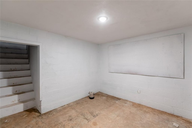 unfurnished room featuring unfinished concrete flooring and concrete block wall