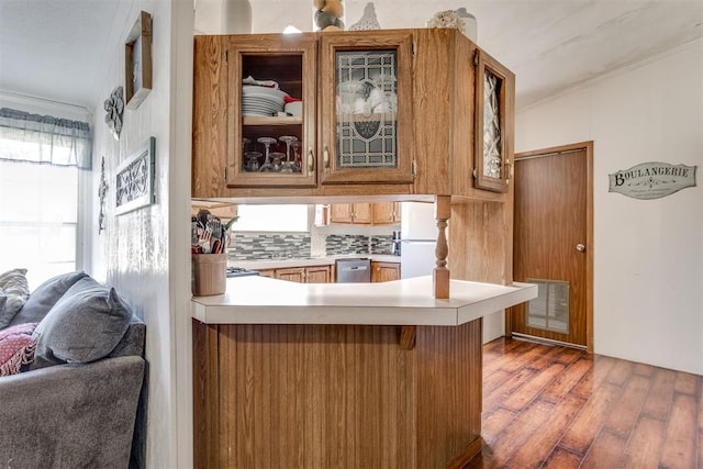 kitchen featuring visible vents, light countertops, a peninsula, freestanding refrigerator, and wood finished floors